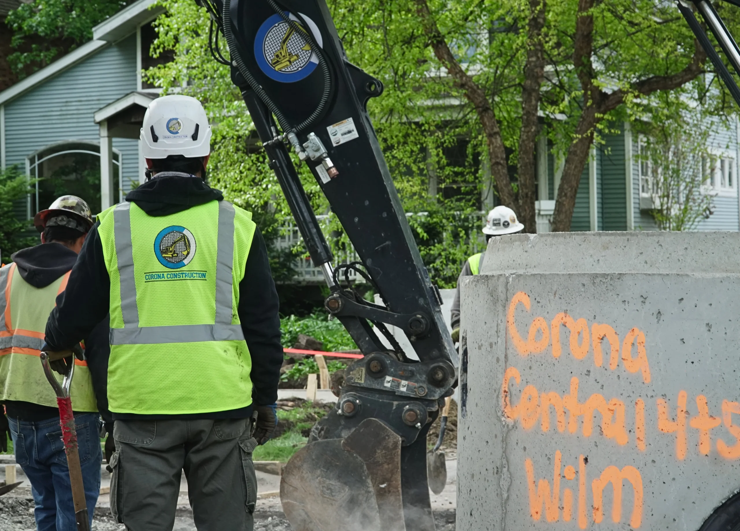 Corona Construction crew installing underground utility infrastructure with an excavator and precast concrete utility structure.